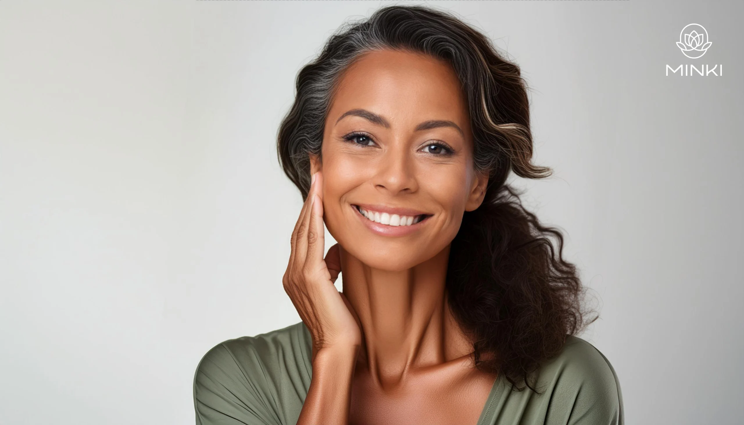 Mujer sonriente tocándose suavemente la cara, mostrando piel saludable y cuidada esta feliz por saber que tipo de piel tiene